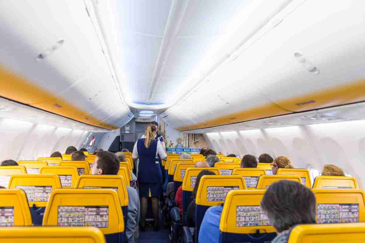 Interno dell'abitacolo di un aereo con hostess e passeggeri