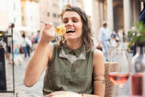 turista che mangia un piatto di spaghetti tra le vie di Roma