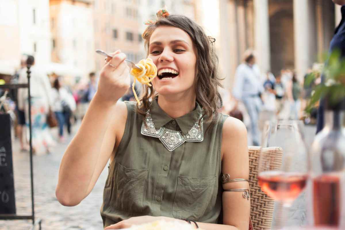 turista che mangia un piatto di spaghetti tra le vie di Roma